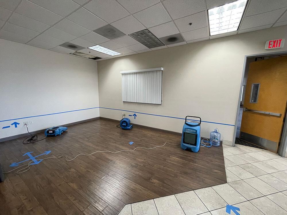 Commercial office water mitigation with blue tape marking mapped moisture along the walls