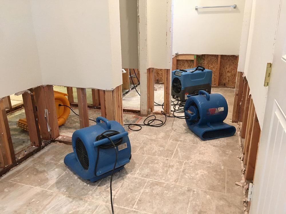Kitchen flood cut with wet lower drywall removed and wall cavities being dried after a water leak