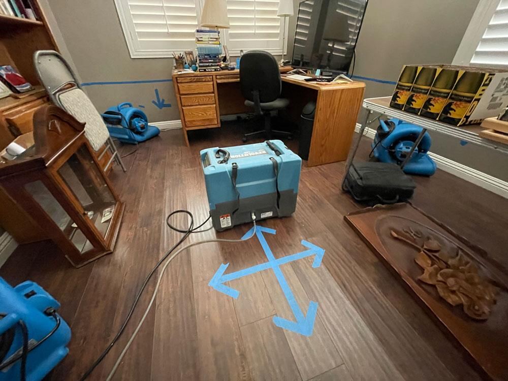Blue Arrow Restoration technicians drying a home office hardwood floor with commercial air movers and a dehumidifier
