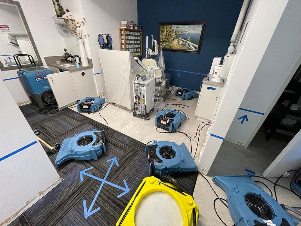 Medical office carpet water damage being dried with equipment protected under plastic sheeting