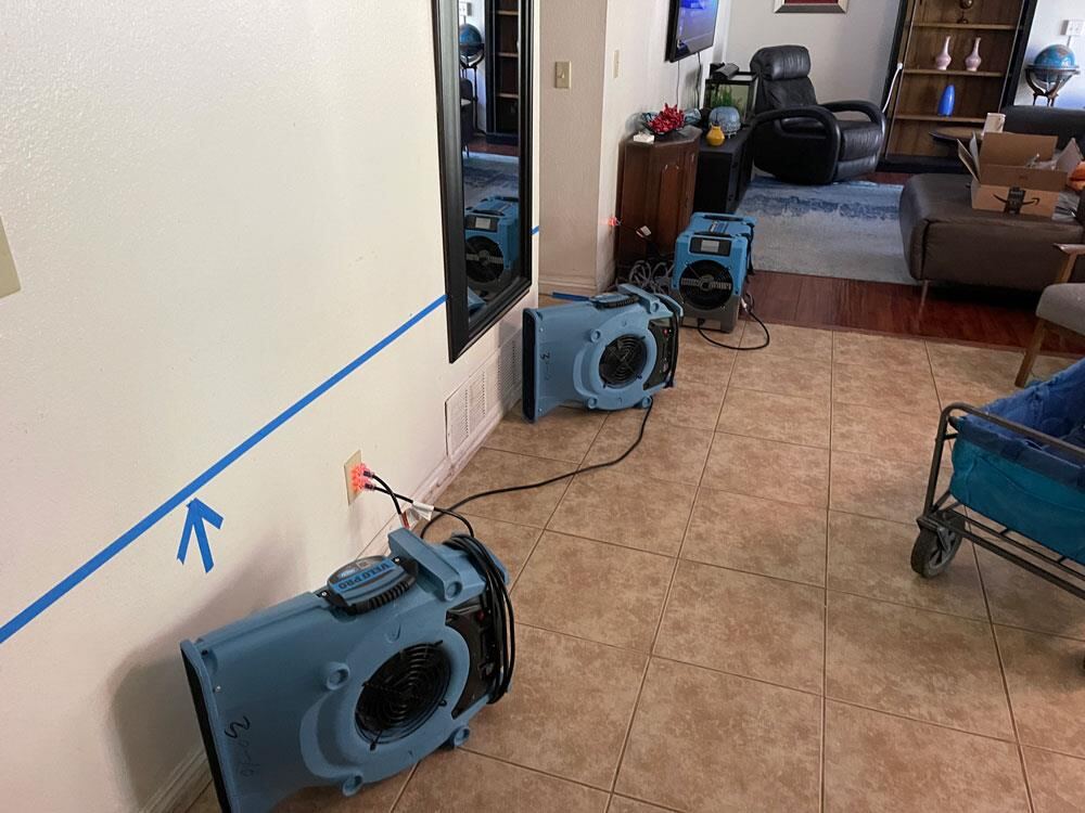 Blue tape marking the mapped wet line on living room walls with air movers along the wall